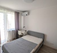 A stylish bedroom with a bed, a table, and a wooden decor floor in a two-room apartment.