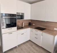 A kitchen in a 2-room apartment with built-in appliances and a wooden decor floor.