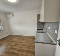 Studio apartment with a kitchenette and wooden decor flooring, air conditioning, and a window.