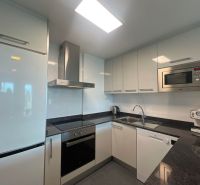 A kitchen in a holiday apartment with white cabinets, appliances, and a black countertop.