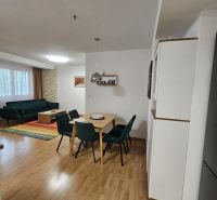 Dining room in a 3-room apartment with a wood-patterned floor and a sofa.