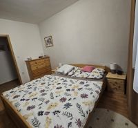 A bedroom in a 3-room apartment with a bed, a dresser, and a floor with a wooden decor.