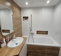 A bathroom in a 3-room apartment with a bathtub and wood decor.