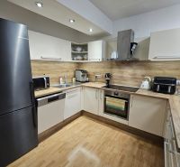A kitchen in a 3-room apartment with a wood-patterned floor and modern appliances.