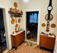 A hallway in a 3-room apartment with furniture, a carpet, and wooden decor on the walls.