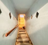 A narrow staircase with walls decorated with paintings in a 3-room apartment.