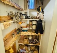 A pantry with shelves in a 3-room apartment, full of kitchen utensils and canning jars.