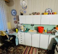 A kitchen in a 3-room apartment with curtains, lace decorations, and antique furniture.