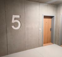 Concrete wall with the number five and wooden doors in a two-room apartment.