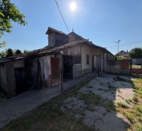 A family house in Nesvady with a damaged roof and a sunny yard.