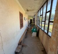 A narrow hallway with a veranda in a family house with old windows and cracked walls.