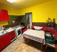 A kitchen in a family house with red furniture, a table, and an electric stove.