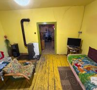 A room in a family house with a stove, yellow walls, and a floor with a wooden decor.