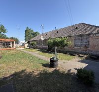 A family house in Nesvady with an unmaintained facade, a wooden pergola, and a landscaped garden.