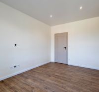 An empty room with a wooden decor floor and light walls in a family house.