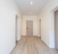 A hallway in a family house with a wooden decor floor and white walls.