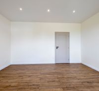 A room with a wooden decor floor and white walls in a family house.