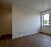 A room in a family house with a wooden decor floor and a large window.