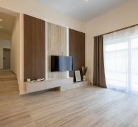 Living room in a family house with a wooden decor floor and a television on the wall.