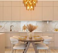 Kitchen area with dining table, beige cabinets, wood-patterned floor, light fixture.