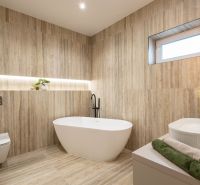 A bathroom in a family house with a wooden decor floor, a bathtub, and decorative lighting.
