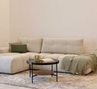 A bright interior with a comfortable sofa, a coffee table, and a wooden decor floor.