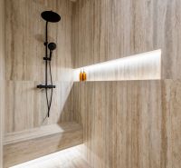 Shower enclosure with natural stone tiles and black fittings in a family house.
