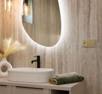 A bathroom in a family house with an oval mirror, a sink, and lights.