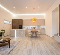 A kitchen and living room in a family house with a decorative light fixture and a wooden decor floor.