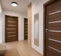 A hallway with a wood-patterned floor, a mirror, and Scandinavian furniture in a three-room apartment.