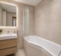 A bathroom in a 3-room apartment with a bathtub, a sink, and a floor with a wooden decor.