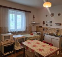A kitchen in a family house with a microwave, tiles, a table, and a sink.