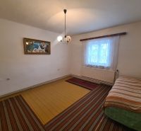 Interior of a family house with a bed, a painting, and a window with curtains.