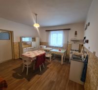 A kitchen in a family house with a wooden decor floor, simple furniture, and a dining table.