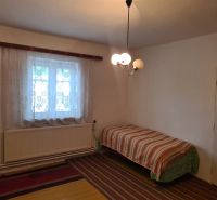 A simple room with a bed and a window, family house, carpet and curtains.