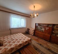 A room with a sofa bed, an older display cabinet, and a curtain, in a family house.