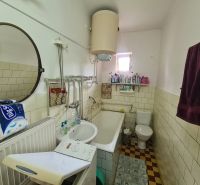 Bathroom with a mirror, sink, bathtub, and washing machine in a family house.