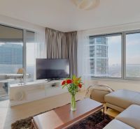 Bright living room with wood-patterned flooring, a corner sofa, and a television.