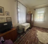 A room with a carpet, table, and TV in a family house. Vintage decorations on the walls.