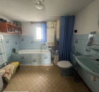 A bathroom in a family house with blue tiles and a bathtub.