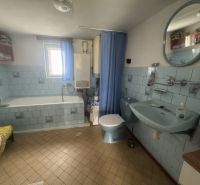 A bathroom in a family house with blue tiles and a bathtub.
