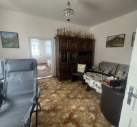 A room in a family house with a richly decorated cabinet and comfortable seating.