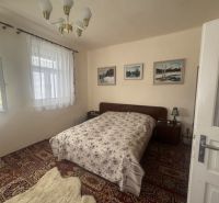Bedroom in a family house with a bed, carpet, and curtains on the windows.