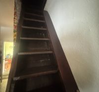 A staircase leading up in a family house with dark wooden steps.