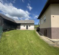 A family house in Orlov with a well-maintained grassy garden and adjacent farm buildings.