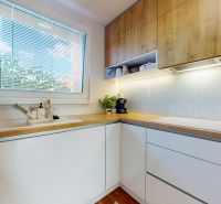 A bright kitchen with white cabinets and wooden decor in a 3-room apartment.