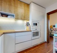 A kitchen in a 3-room apartment with a wooden decor floor and built-in appliances.