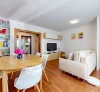 Living room in a three-room apartment with a wooden decor floor and a dining table.
