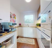 A kitchen in a 3-room apartment with modern appliances and a wooden decor floor.