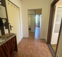 A hallway in a 2-room apartment with simple furnishings and linoleum flooring.